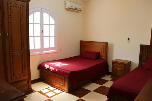 ein Schlafzimmer mit einem roten Bett und einem Fenster in der Unterkunft Sandy House in Madinat as-Sadis min Uktubar