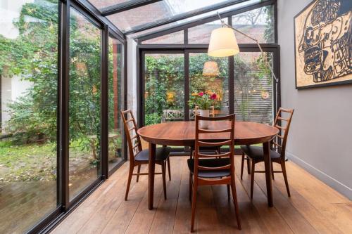 a dining room with a table and chairs and windows at Spectacular Family Home with GardenOlympiades in Paris