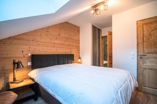 een slaapkamer met een bed en een houten muur bij Résidence LUMI BATIMENT B - Appartement LUMI B pour 4 Personnes 014 in Valmorel