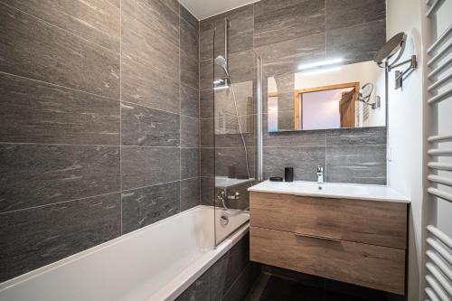 een badkamer met een wastafel, een bad en een spiegel bij Résidence LUMI BATIMENT B - Appartement LUMI B pour 4 Personnes 014 in Valmorel