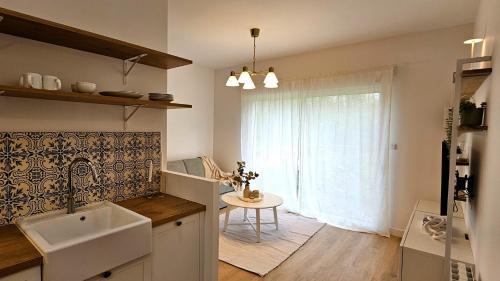 uma cozinha com um lavatório, uma mesa e uma janela em Appartement Le Porto em Cholet