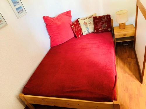 a bed with red sheets and pillows in a room at Résidence Rond-point Des Pistes Iii - 2 Pièces pour 4 Personnes 98 in Val-d'Isère