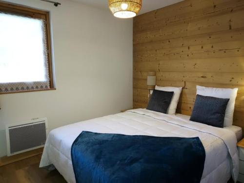 ein Schlafzimmer mit einem großen Bett und einer Holzwand in der Unterkunft Résidence LUMI BATIMENT B - Appartement LUMI B pour 4 Personnes 754 in Valmorel