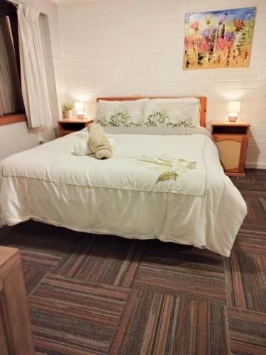 a bedroom with a large white bed with a rug at Koloona in Wollongong