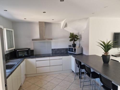 une cuisine avec des armoires blanches et des comptoirs noirs dans l'établissement VILLA FAMILIALE AVEC PISCINE PROCHE DE TOUTES LES PLAGES, à Villeneuve-lès-Maguelone