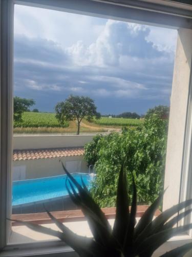 une fenêtre avec vue sur la piscine dans l'établissement VILLA FAMILIALE AVEC PISCINE PROCHE DE TOUTES LES PLAGES, à Villeneuve-lès-Maguelone