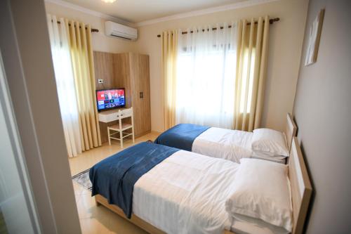 een hotelkamer met 2 bedden en een televisie bij Villa Solitude in Berat