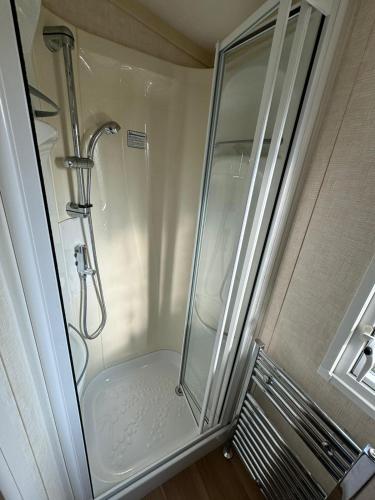 a shower with a glass door in a bathroom at Golden Anchor - The Chamonix - Coastal Caravan Breaks in Chapel Saint Leonards