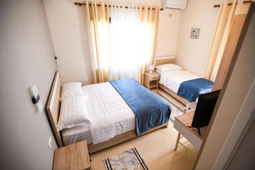een kleine slaapkamer met 2 bedden en een televisie bij Villa Solitude in Berat