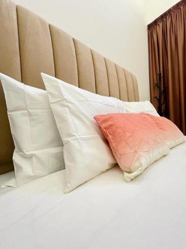 un cuscino posto sopra un letto con cuscini bianchi di Property management aéroport med V international a Dah Hammou Ben Cheïkh