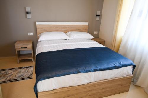 a bedroom with a large bed with a blue blanket on it at Villa Solitude in Berat