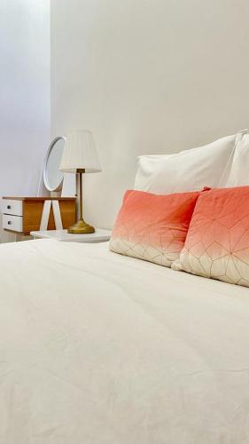 un letto bianco con cuscino rosso e lampada di Property management aéroport med V international a Dah Hammou Ben Cheïkh
