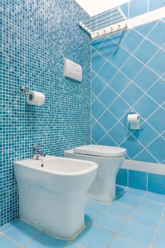 a blue tiled bathroom with a toilet and a sink at Settessenze Residence & Rooms in Agropoli