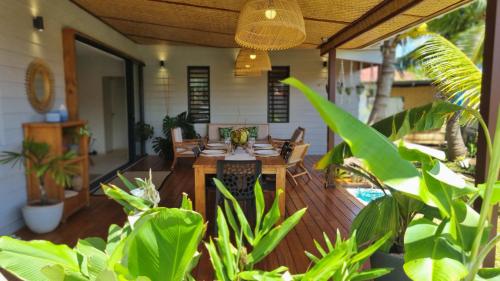 un porche con una mesa de madera y algunas plantas en Raahere Lodge - near the city center, en Papeete
