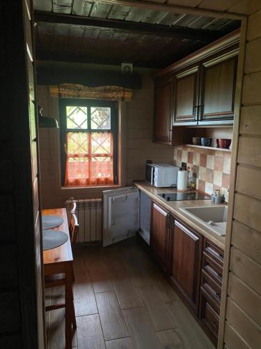 Shcherbovets的住宿－Садиба Остра，厨房配有木制橱柜、水槽和窗户。