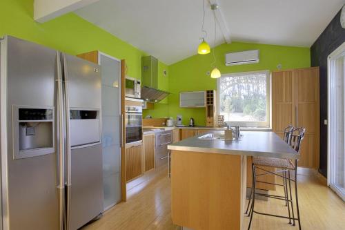 a kitchen with a stainless steel refrigerator and wooden cabinets at Villa des Sables - Welkeys in Seignosse