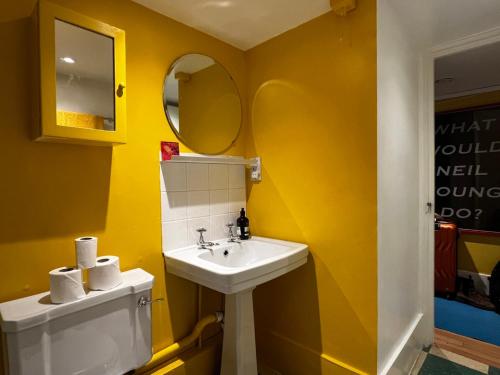 a yellow bathroom with a sink and a mirror at Comfy child/dog friendly garden flat heart Camden in London