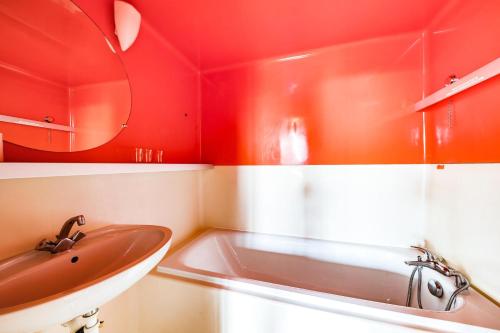 La salle de bains est pourvue de murs rouges, d'un lavabo et d'un miroir. dans l'établissement Résidence Lauzieres - Studio 5 personnes skis aux pieds et proche des commerces dans le village du Charvet à Arc 1800 MAE-2057, à Arc 1800