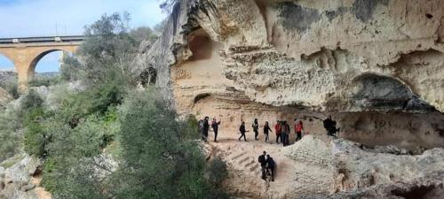 a group of people walking on a cliff with a bridge at L' Archè in Castellaneta