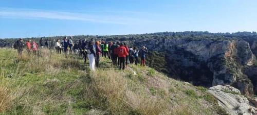 a group of people walking on the edge of a mountain at L' Archè in Castellaneta