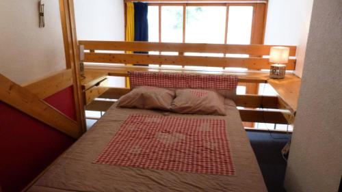 ein kleines Bett in einem Zimmer mit einem großen Fenster in der Unterkunft Résidence Aiguille Grive Bat Ii - 2 Pièces pour 5 Personnes 75 in Arc 1800