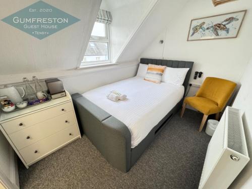 a small bedroom with a bed and a chair at Gumfreston Guest House in Tenby