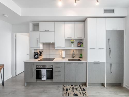 uma cozinha com armários brancos e um lavatório em Designer One Bedroom Suite - Entertainment District Toronto em Toronto