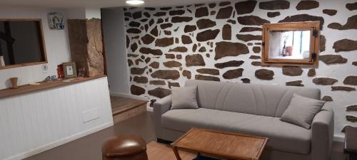 sala de estar con sofá y pared de roca en Casa da Eiriña, en Amés