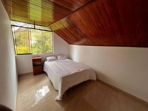 um quarto com uma cama e uma grande janela em Casa de Campo Oro Verde San Jose em Oxapampa