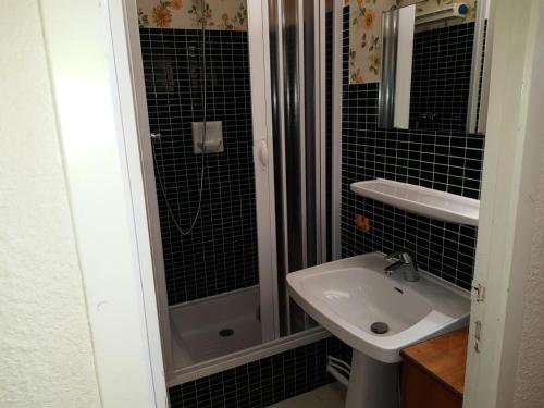 La salle de bains est pourvue de carrelage noir, d'un lavabo et d'une douche. dans l'établissement Résidence Vallonpierre A - Studio cabine 4 personnes MAE-2818, à Orcières