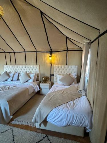a bedroom with two beds in a tent at Erg Chebbi Sahara Camp in Merzouga