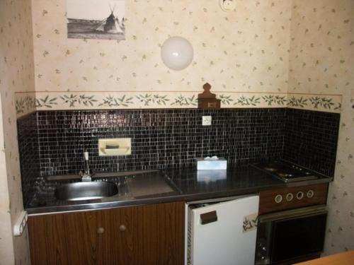 une cuisine avec un évier et un mur carrelé noir dans l'établissement Résidence Roches Rousses A - 2 pièces 6 personnes MAE-2845, à Orcières