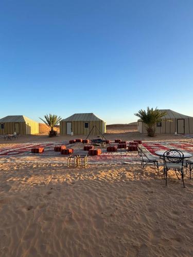 a group of benches sitting on the sand in the desert at Erg Chebbi Sahara Camp in Merzouga