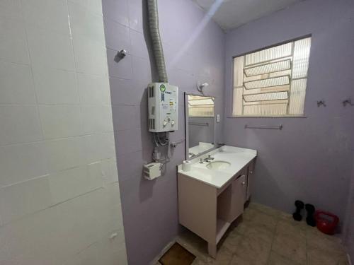 Baño blanco con lavabo y espejo en Quarto simple em Ipanema, en Río de Janeiro