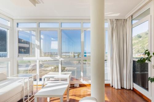 a living room with white furniture and large windows at Playa, río y monte en 1ª linea in Orio
