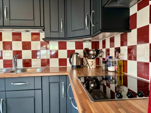 une cuisine avec des armoires noires et un four à plaques de cuisson dans l'établissement Appartement plein sud - Thônes, à Thônes