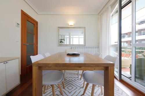 a dining room with a wooden table and white chairs at Playa, río y monte en 1ª linea in Orio