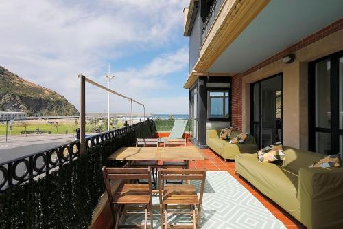 uma varanda com sofás e mesas e vista para a praia em Playa, río y monte en 1ª linea em Orio