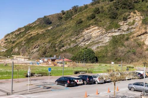a parking lot with cars parked in front of a mountain at Playa, río y monte en 1ª linea in Orio