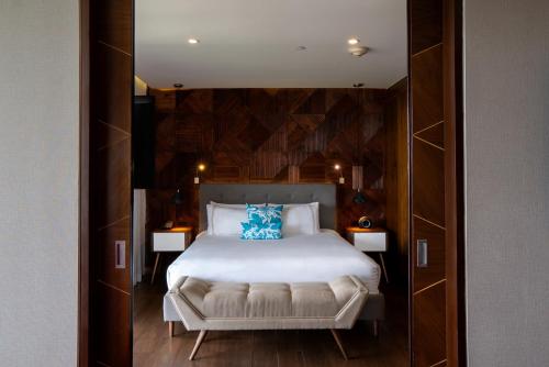 a bedroom with a white bed with a blue pillow at The Fives Downtown Hotel & Residences, Curio Collection by Hilton in Playa del Carmen