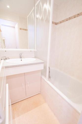 une salle de bain blanche avec un lavabo et une baignoire dans l'établissement Résidence Les Portes De La Vanoise - LES PORTES DE LA VANOISE - SB408B MAE-3053, à Villarodin-Bourget