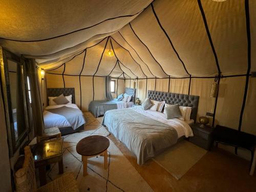 a bedroom with two beds in a tent at Erg Chebbi Sahara Camp in Merzouga