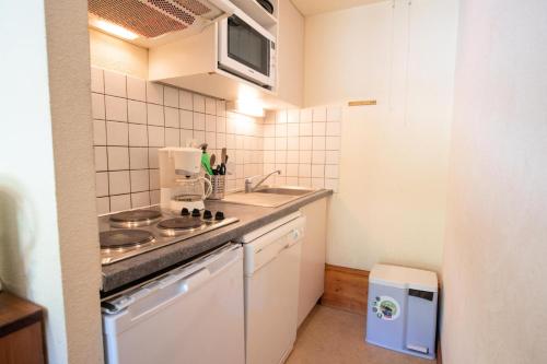 une petite cuisine avec un évier et une cuisinière dans l'établissement Résidence Les Arolles - LES AROLLES - AR09B MAE-3056, à Villarodin-Bourget