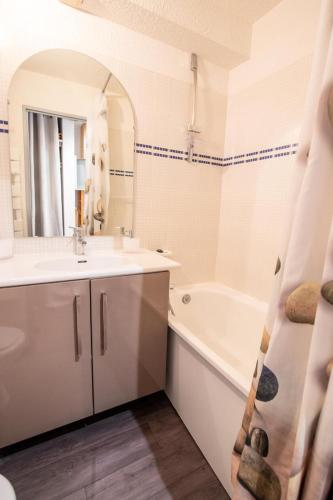 une salle de bain avec un lavabo, une baignoire et un miroir dans l'établissement Résidence Thabor D - THABOR D - THAD138 MAE-3090, à Modane