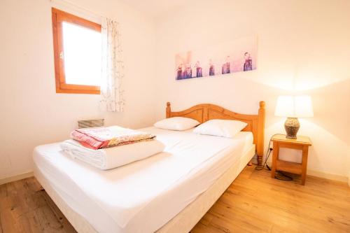 un lit blanc dans une chambre avec une fenêtre dans l'établissement Résidence Belvedere Busseroles - RESIDENCE LE BELVEDERE 