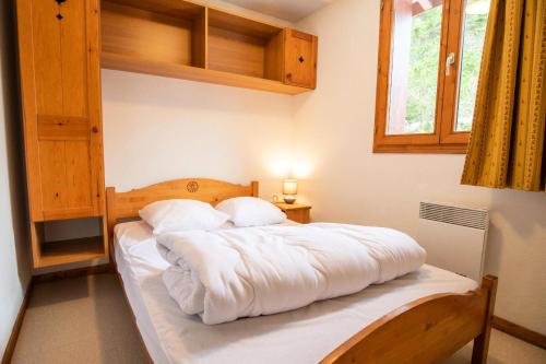 een slaapkamer met een bed met witte lakens en een raam bij Chalet Arrondaz J - 3 Pièces pour 6 Personnes 193111 in Modane