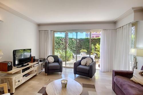 un salon avec deux chaises et une télévision dans l'établissement 2 bdr apartment with garden next to the Croisette, à Cannes