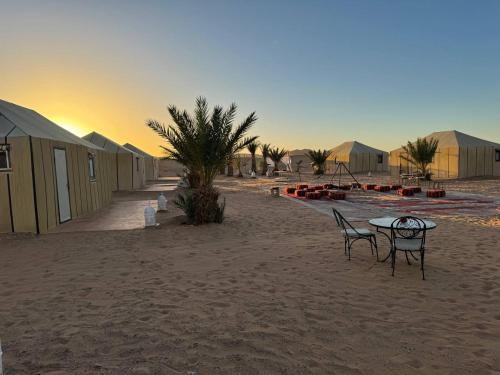 a table and two chairs on a sandy beach at Erg Chebbi Sahara Camp in Merzouga