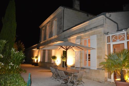 une table et des chaises avec un parasol en face d'un bâtiment dans l'établissement Château La Tuilière Villa with pool and it's own wineyard, à Saint-Ciers-de-Canesse