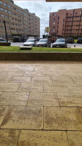 a sidewalk with cars parked in a parking lot at Apartamento 50mt Praia Póvoa Varzim in Póvoa de Varzim